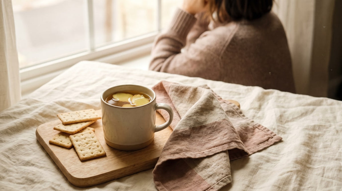 Tasse Ingwertee mit frischem Ingwer und ein paar Cracker am Fenster im sanften warmen Licht